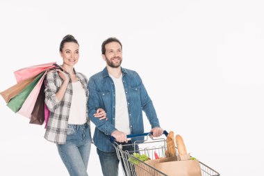 portrait of smiling couple with shopping bags and paper packages with grocery in shopping cart isolated on white