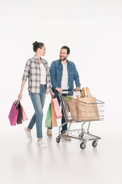 пара с пакетами покупок и бумажные пакеты, полные продуктов питания в корзине изолированы на белом
