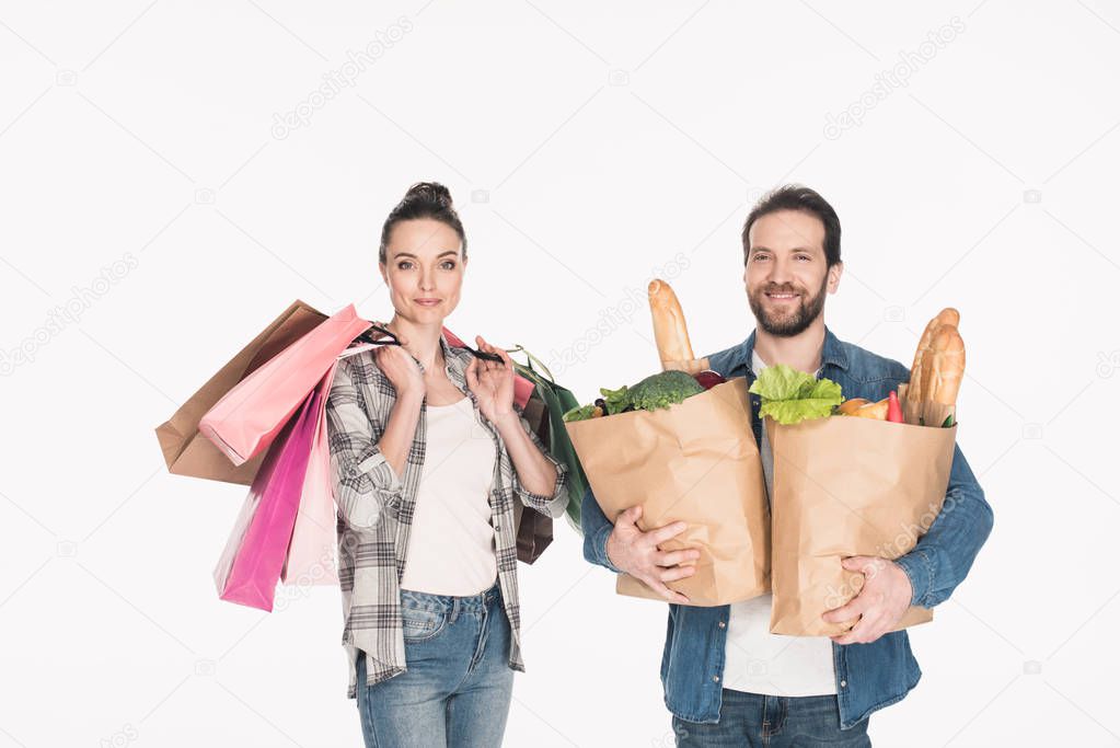 portrait of wife and husband holding shopping bags and paper packages full of food isolated on white