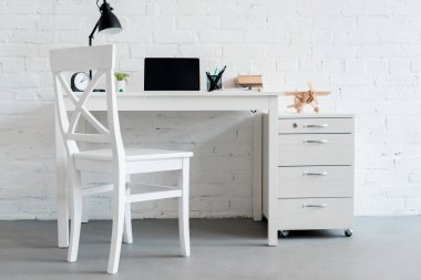 Beyaz tuğla duvar önünde evde dizüstü bilgisayar ile modern çalışma masası