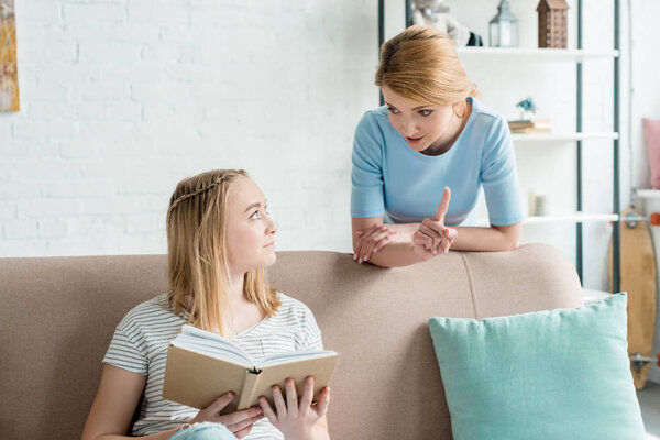 мать учит дочь дома, пока она делает домашнее задание
