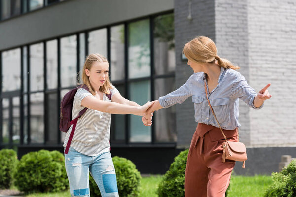 mother pulling her daughter and forcing to go somewhere