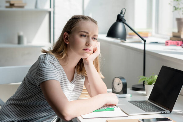 thoughtful teen student girl doing homework and looking away