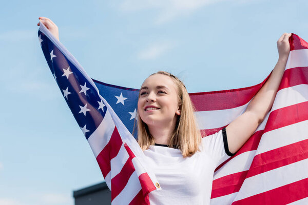happy teen girl with usa flag in front of blue sky