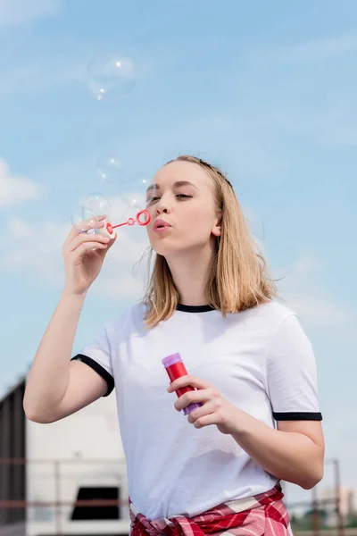 stock image beautiful teen girl blowing soap bubbles in front of blue sky