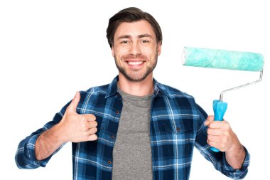 boya silindiri tutarak ve beyaz arka plan üzerinde izole jest yukarı yapıyor gülümseyen genç adam 