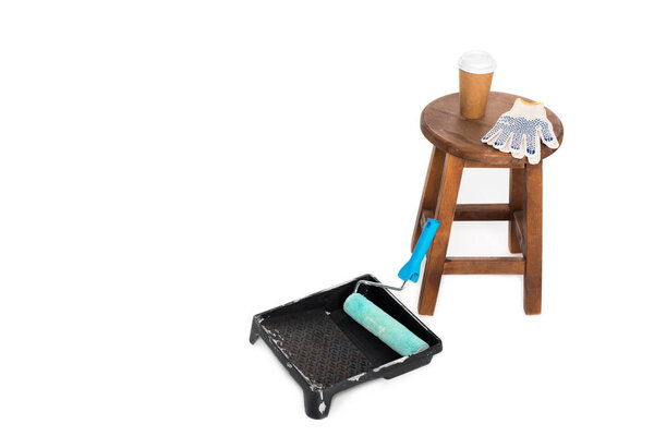 closeup shot of chair, coffee cup, protective gloves, roller tray and paint roller isolated on white background 