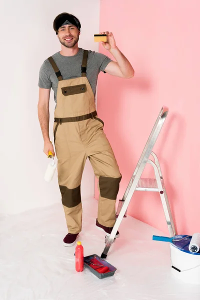 Young Man Headband Working Overall Standing Ladder Holding Credit Card — Free Stock Photo