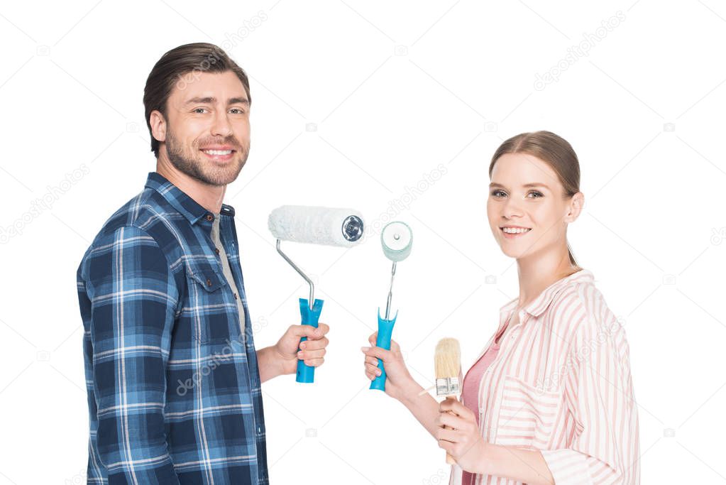 smiling young couple with paint rollers and paint brush isolated on white background 