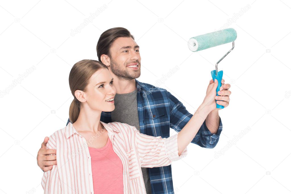 smiling man teaching girlfriend painting by paint roller isolated on white background 