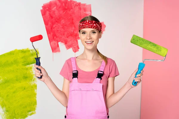 Усміхнена Жінка Робочому Цілому Тримає Фарбувальні Ролики Перед Пофарбованою Стіною — стокове фото
