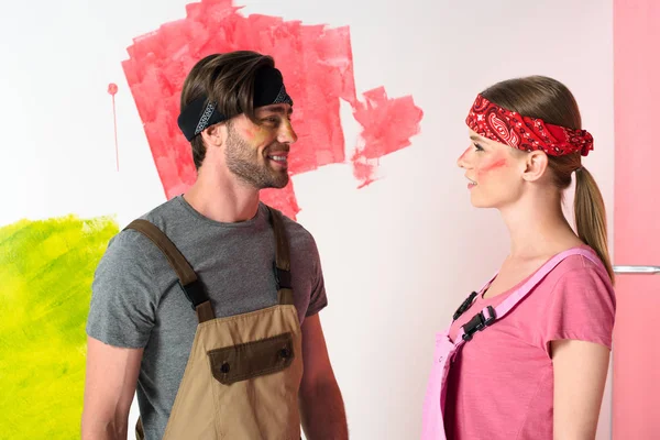 young couple in working overalls with painted faces looking at each other