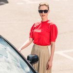 Vista de ángulo alto del modelo femenino joven con estilo en gafas de sol que abren la puerta del coche