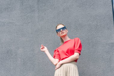 taş duvar önünde güneş gözlükleri şık genç kadın modelinin düşük açılı görünüş 