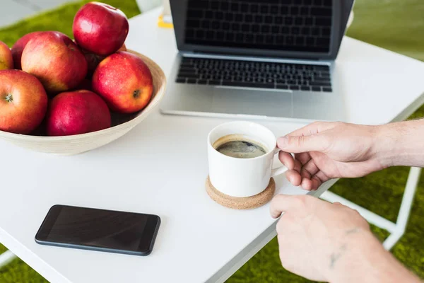 Cropped Image Man Taking Coffee Cup Table Smartphone Laptop Apples — Stock Photo, Image