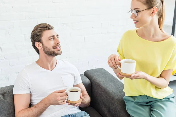 Sonriente Joven Pareja Teniendo Conversación Bebiendo Café Tazas Casa — Foto de Stock