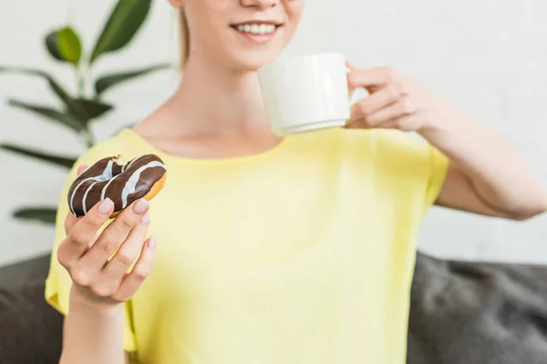 Recortado Disparo Mujer Joven Beber Café Comer Donut Casa —  Fotos de Stock