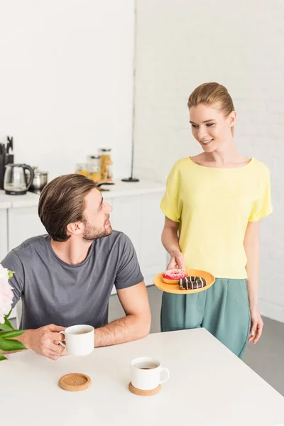 Smiling Woman Holding Plate Donuts Talking Smiling Boyfriend Sitting Table — Stock Photo, Image