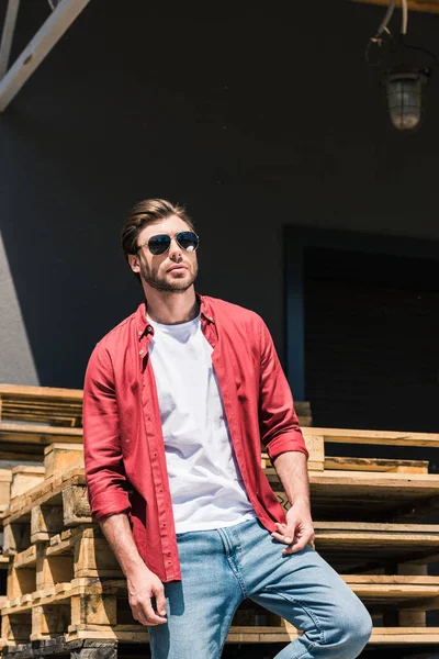 Jovem Homem Elegante Óculos Sol Posando Perto Paletes Madeira — Fotografia de Stock