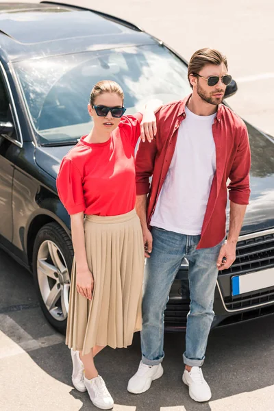 Elegante Casal Modelos Óculos Sol Posando Perto Carro Preto — Fotos gratuitas