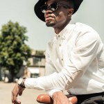 Stylish man wearing white shirt leaning his bicycle on street
