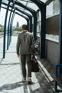 Stylish confident businessman walking on train station clipart