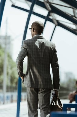 African american businessman wearing suit walking on train station clipart