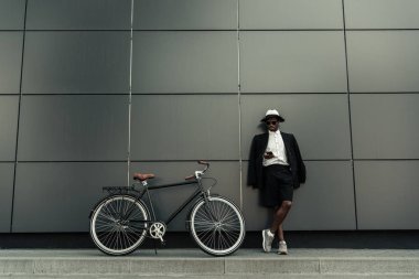 Fedora şapka onun bisikletle dururken Smartphone kullanarak moda Afrikalı-Amerikalı adam