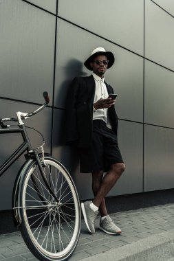 Beyaz gömlek ve onun bisikletle dururken smartphone kullanarak ceket giyen şık adam