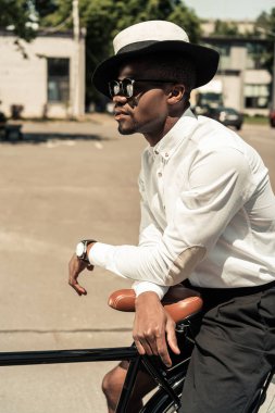 Yakışıklı genç Afro-Amerikan adam bisikletine sokakta yaslanmış