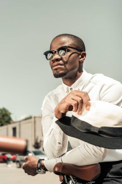 Yakışıklı genç Afro-Amerikan adam şehir bisikletle eğilerek güneş gözlüğü