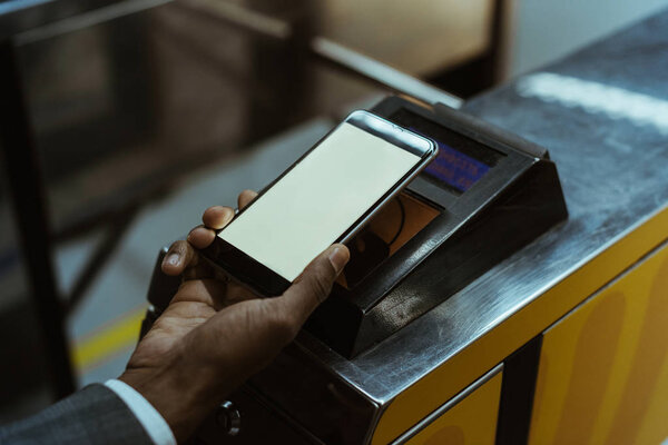 Крупный план африканского американца, оплачивающего проезд на общественном транспорте через смартфон
