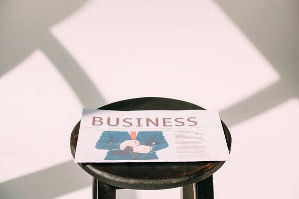 close-up view of business newspaper on wooden stool on white