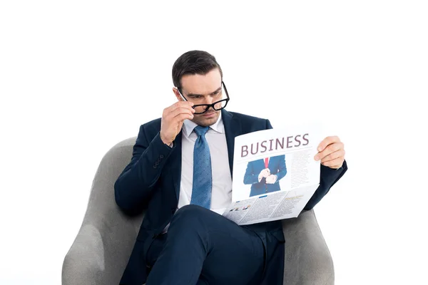 Focused Businessman Adjusting Eyeglasses Reading Newspaper While Sitting Armchair Isolated — Stock Photo, Image