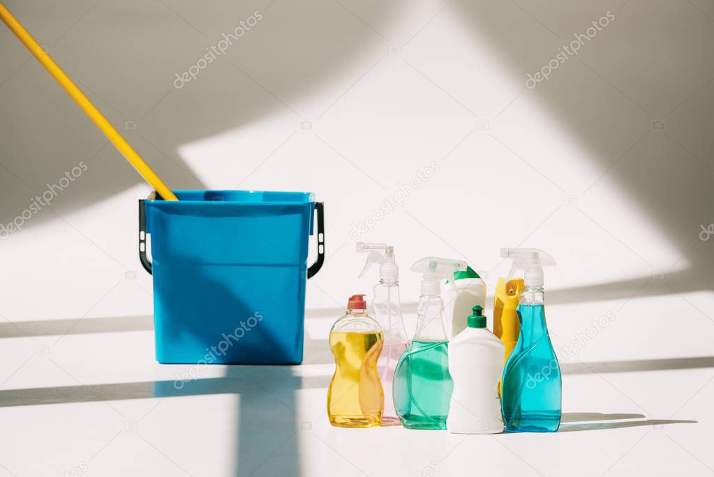 various cleaning products, mop and bucket on white
