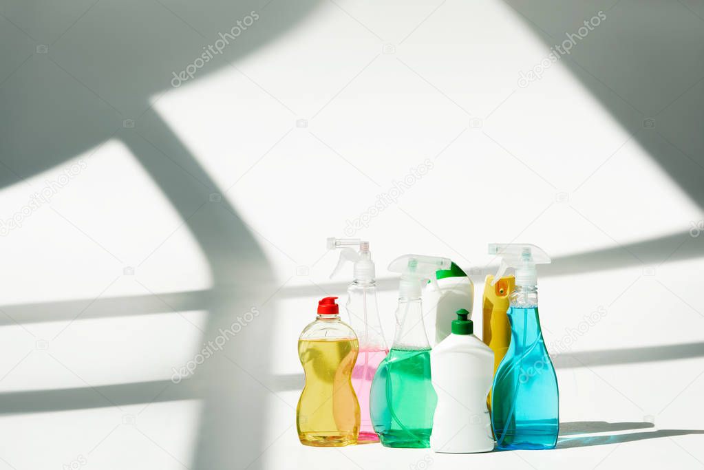 various bottles and sprayers with cleaning products on white