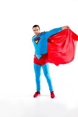 handsome man in superhero costume and cloak looking at camera isolated on white clipart