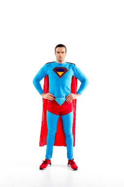 full length view of handsome mid adult superman standing with hands on waist and looking at camera isolated on white clipart