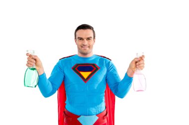 handsome man in superhero costume holding spray bottles and smiling at camera isolated on white  clipart