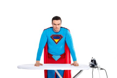handsome male superhero leaning at ironing board and looking at camera isolated on white clipart