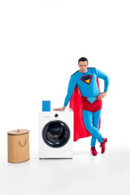 handsome male superhero leaning at washing machine and looking at camera on white clipart