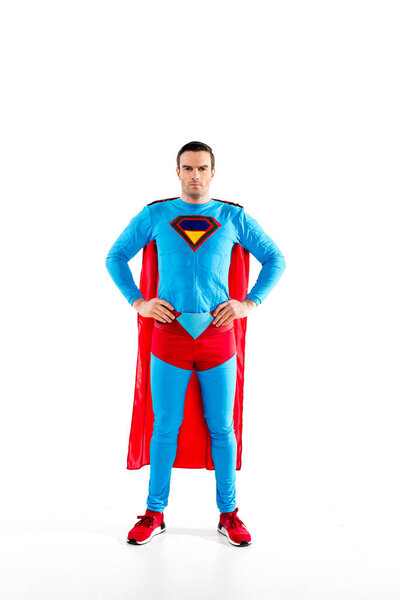 full length view of handsome mid adult superman standing with hands on waist and looking at camera isolated on white