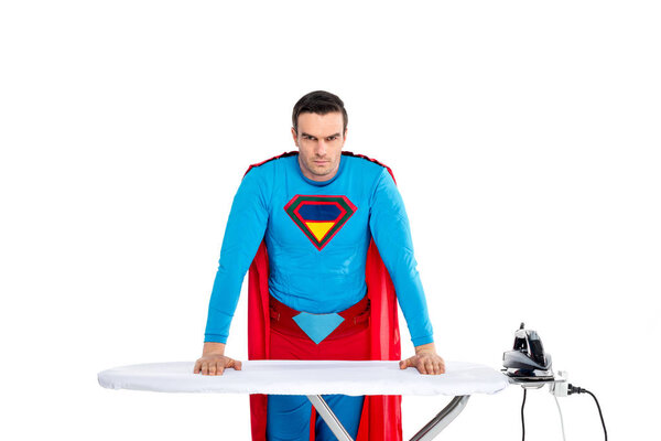 handsome male superhero leaning at ironing board and looking at camera isolated on white