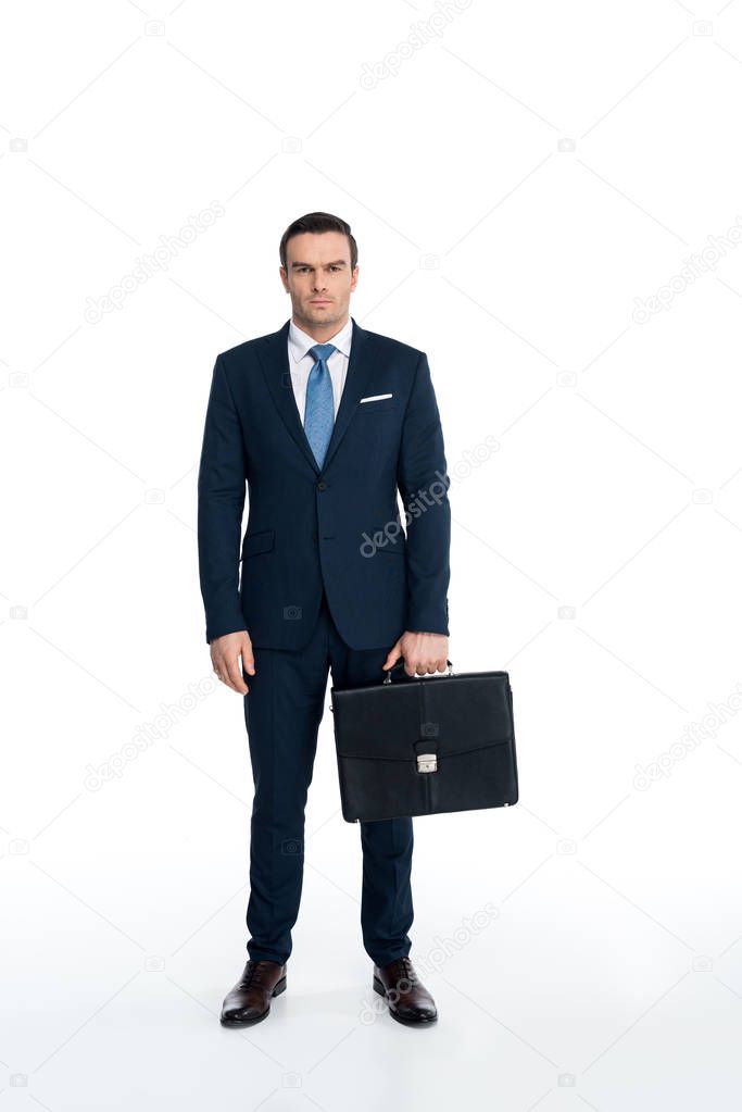 full length view of serious middle aged businessman holding briefcase and looking at camera on white