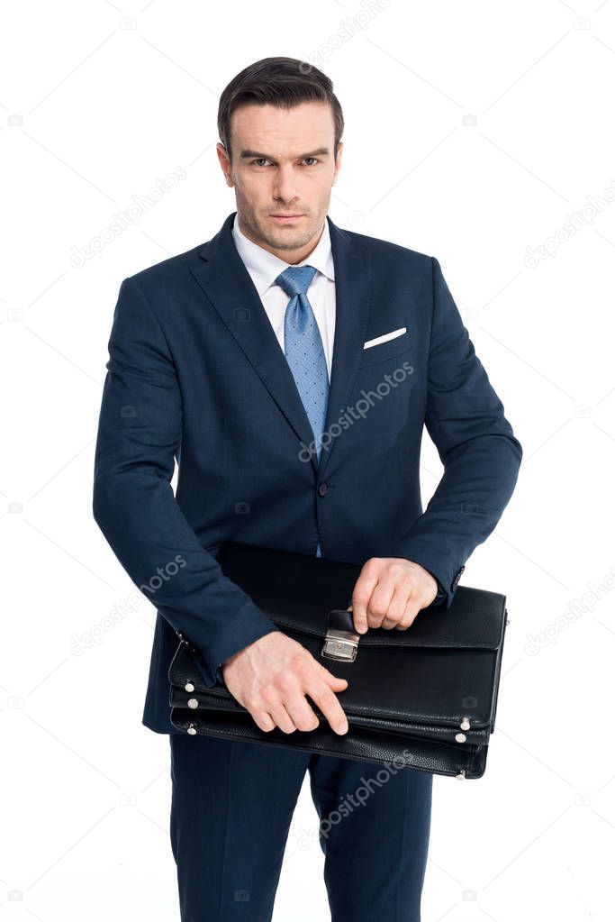 serious middle aged businessman holding briefcase and looking at camera isolated on white