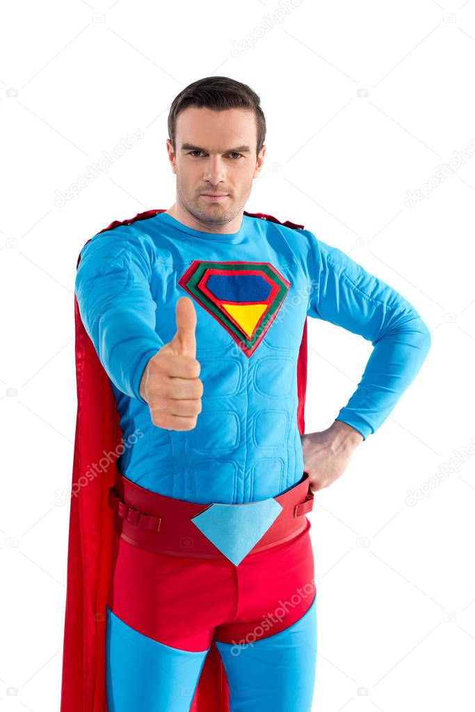 handsome man in superhero costume showing thumb up and looking at camera isolated on white