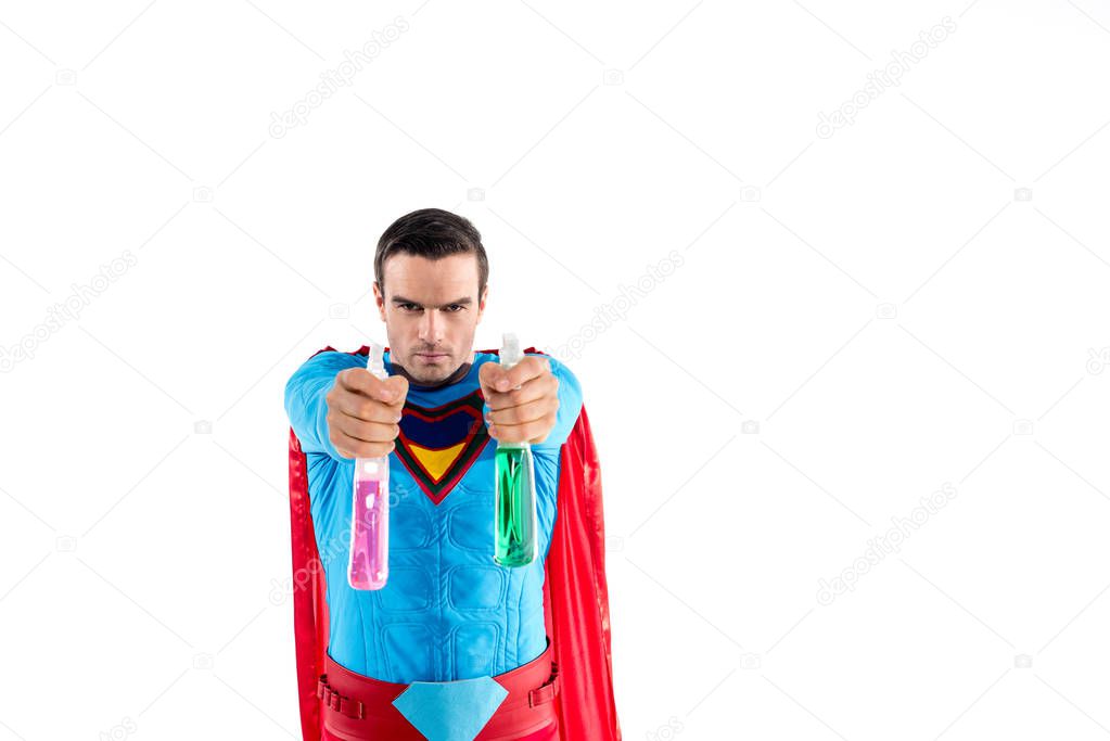 superman holding plastic spray bottles with cleaning liquid and looking at camera isolated on white   
