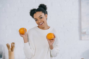 happy young woman with fresh oranges at kitchen