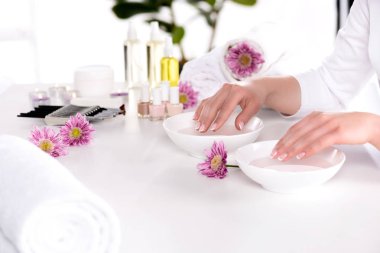 kadının güzellik salonunda banyo masasında görmek çiçek, havlu, mumlar, aroma yağ şişeleri, tırnak cilaları, Krem Konteyner ve manikür çivi için alma kırpılmış görüntü 