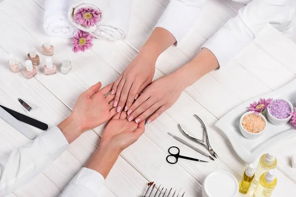 Imagen Recortada Manicura Mirando Las Manos Mujer Mesa Con Flores — Foto de Stock